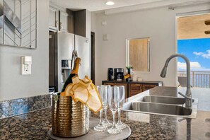 A modern kitchen with a granite countertop, a stainless steel sink, and a bottle of champagne.