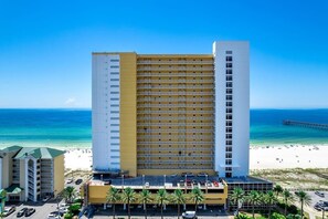 Un hotel de varios pisos con vista al mar, un estacionamiento y un muelle al fondo.