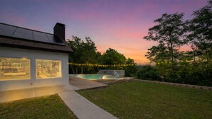 Ein modernes Haus mit Swimmingpool, überdachter Terrasse und Lichterketten.
