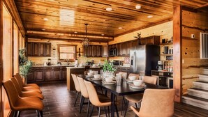 Una cocina moderna con armarios de madera, una isla central y un comedor con sillas y una mesa dispuesta para seis personas.