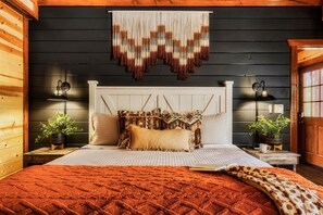 A cozy bedroom with a wooden headboard, a patterned bedspread, and two bedside tables with lamps and potted plants. - New~6 Bed Lux Cabin:Heated Private POOL| Views|Games| Firepit|Dog-friendly! (Sevierville)