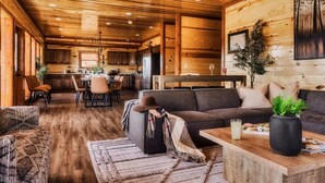 Amplia sala de estar con techo de madera, un sofá, una mesa de centro y un comedor al fondo.