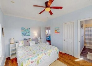 A bedroom with a bed, a ceiling fan, and a door leading to another room. - Beachfront Living! Multi-Generation Beach Home with 360 Water Views (Bolivar Peninsula)