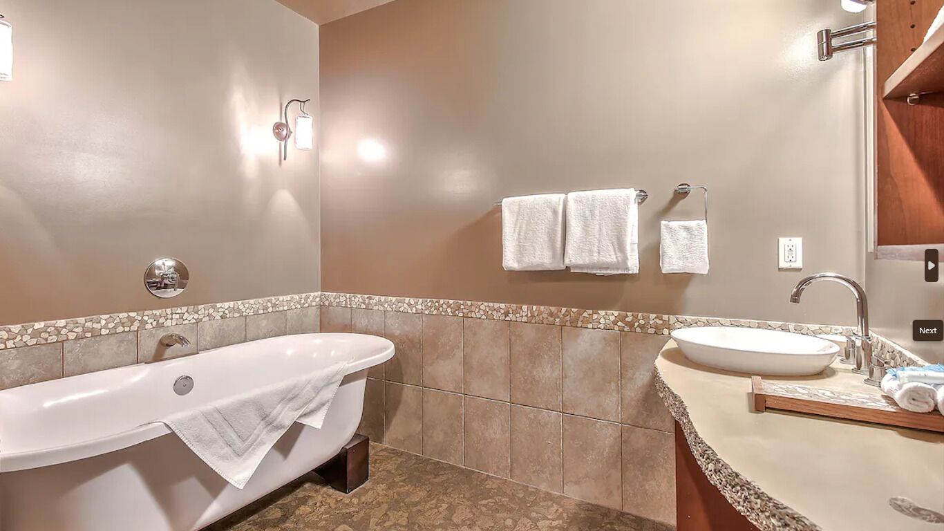 A modern bathroom with a freestanding bathtub, a sink with a vessel basin, and a vanity with a mirror.