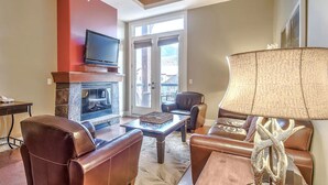Un salon avec des meubles en cuir, une cheminée et un téléviseur.