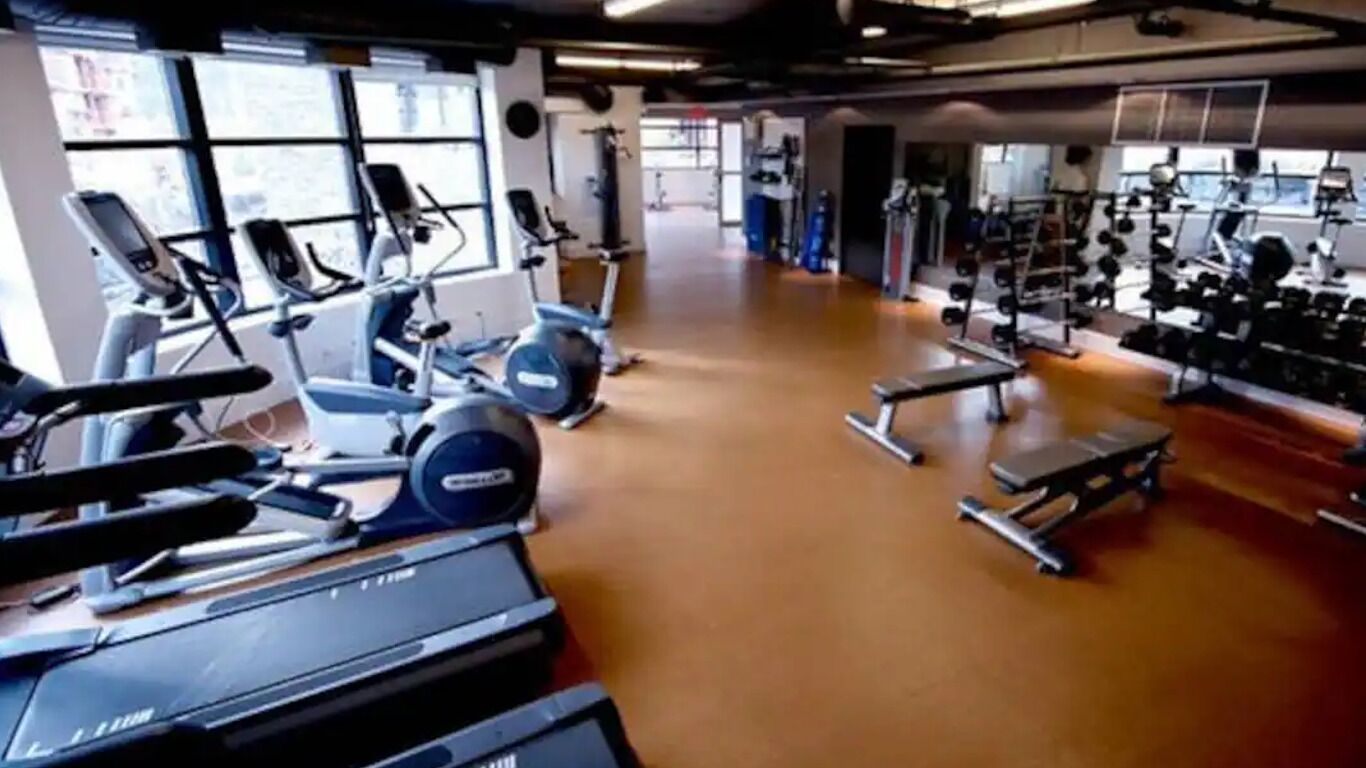 A gym with cardio machines, weightlifting equipment, and a spacious layout.