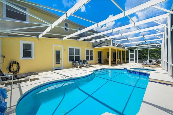 A covered swimming pool with lounge chairs and a patio area.
