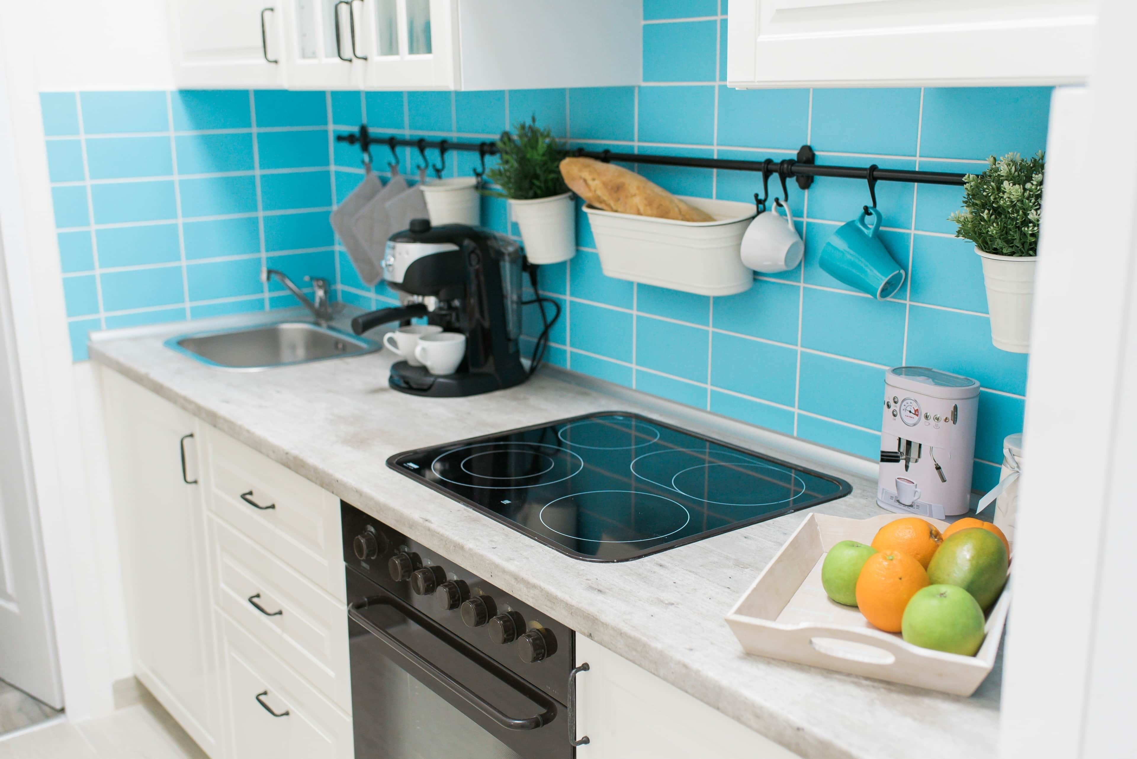 A kitchen with a stove, coffee maker, and fruit bowl.