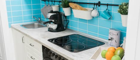A kitchen with a stove, coffee maker, and fruit bowl.