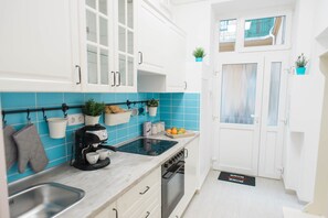 Une cuisine moderne avec des meubles blancs, une cuisinière noire et un dosseret de carrelage bleu.
