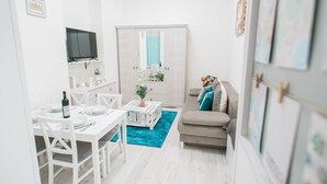 Un espacio habitable moderno con comedor, sofá y televisor montado en la pared.