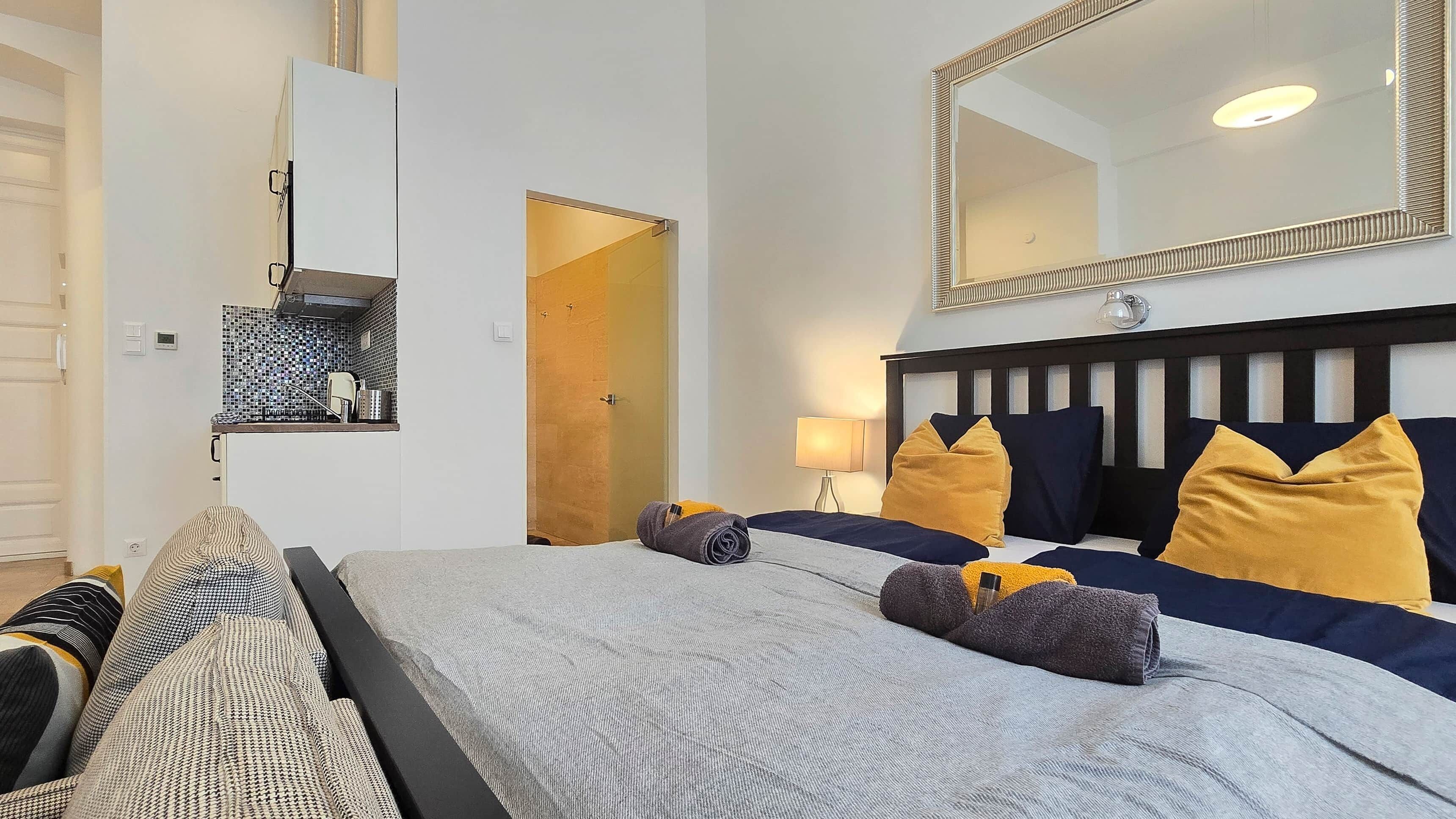 Habitació d'hotel amb un llit, una làmpada de nit, un mirall i vista al passadís.