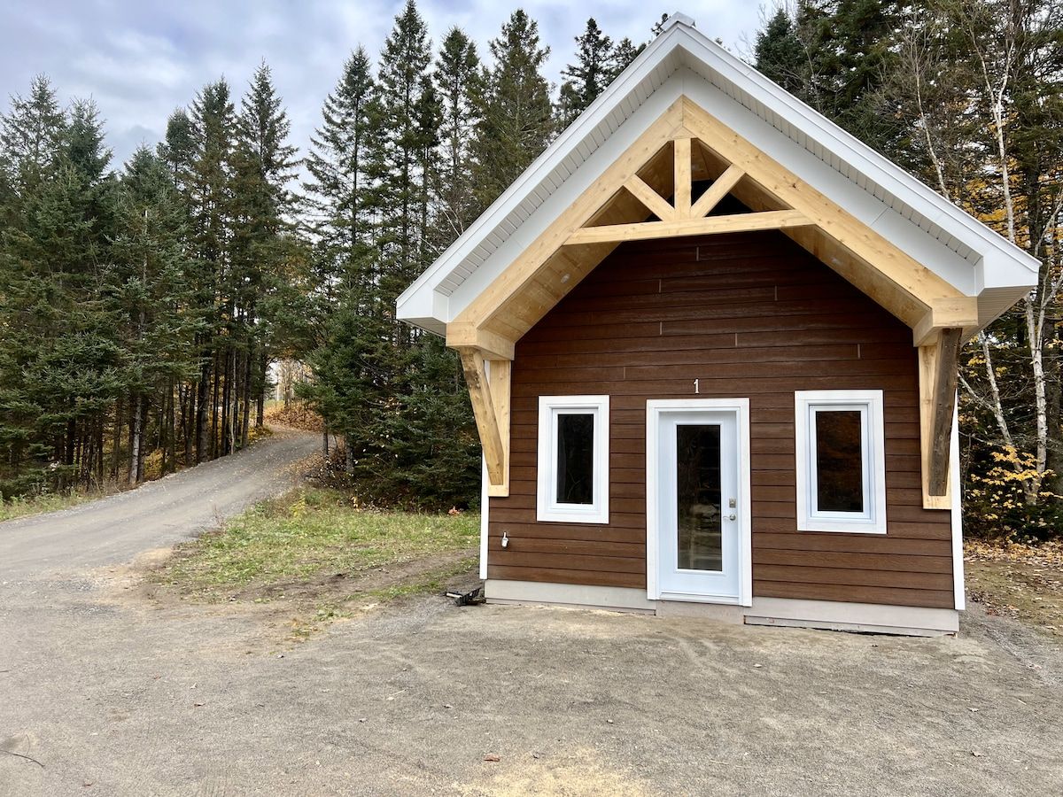 A small cabin with a gabled roof, two windows, and a door.