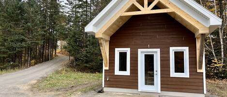 A small cabin with a gabled roof, two windows, and a door.
