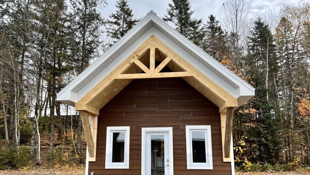 A small wooden cabin with a gabled roof, a central door, and two windows on either side. - Mini-Chalet #2 – Near the River (Saint-Gabriel-de-Valcartier)