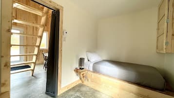 Una camera da letto con letto a soppalco, una scala, un comodino con una lampada e un armadio.