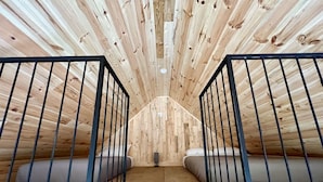 A loft bedroom with a sloped ceiling, two beds, and a central light fixture. - Mini-Chalet #4 – Near the River (Saint-Gabriel-de-Valcartier)