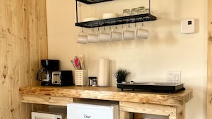 A compact kitchen with a built-in microwave, a white refrigerator, and a wooden countertop. - Mini-Chalet #4 – Near the River (Saint-Gabriel-de-Valcartier)