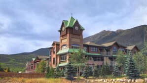 A large, multi-story building with a prominent tower featuring clocks, surrounded by trees and mountains. - Private Hot Tub, Walk to Main St, Close to Ski Resorts, Incredible Views (Firsco)