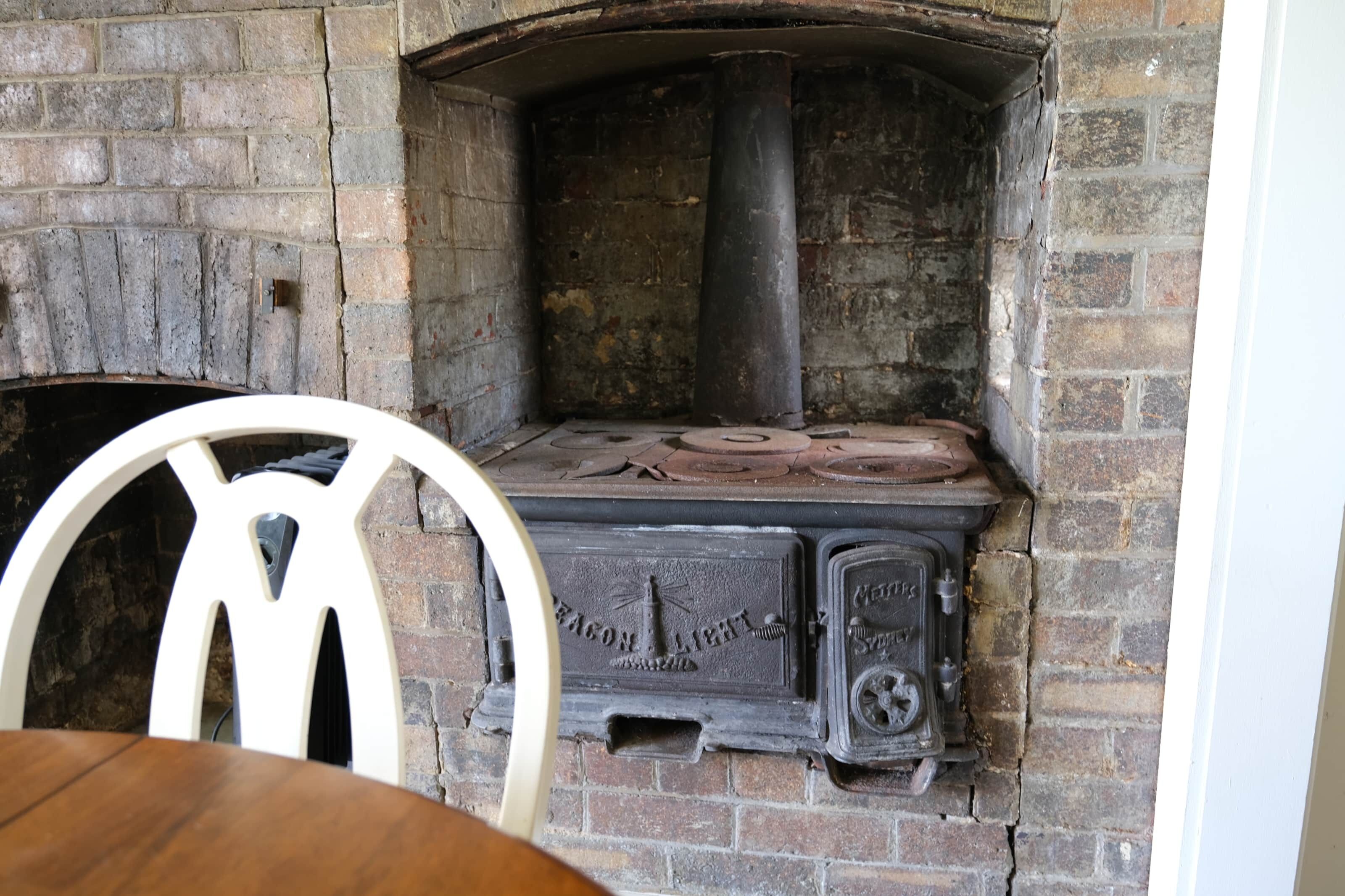 Una chimenea de ladrillo con una silla blanca delante.