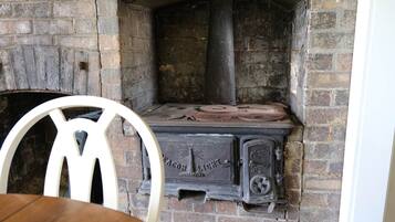 Una chimenea de ladrillo con una silla blanca delante.