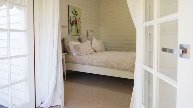 A bedroom with a bed, a painting on the wall, and a window with curtains. - Twodogfolly at Dangarsleigh, Cottage at Dangarsleigh (Armidale)