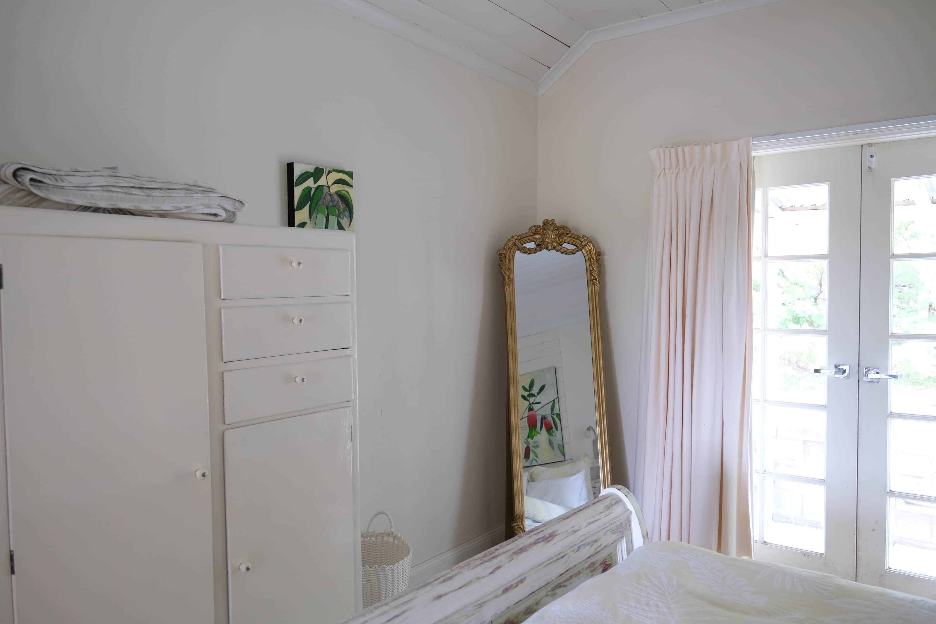 Une chambre à coucher comprenant un lit, une armoire, un miroir et une porte donnant sur un balcon.