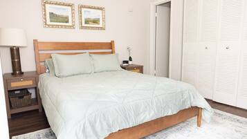 A bedroom with a wooden bed, a nightstand, a lamp, and a wall with two framed pictures.