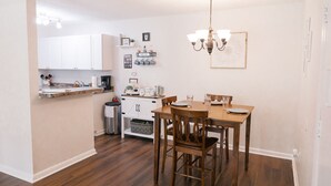 Una cocina compacta con armarios blancos, una mesa de comedor de madera y una araña.
