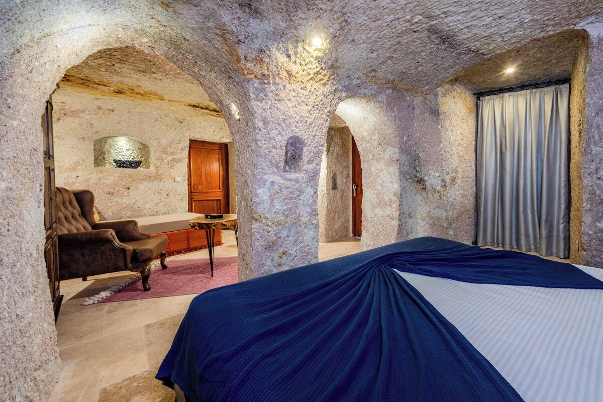 A room with a bed, a chair, a desk, and a window with curtains.