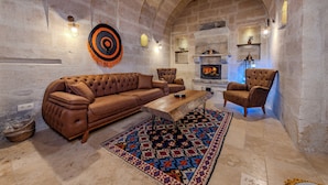 A cozy living room with a brown leather sofa, a wooden coffee table, and a patterned rug. - Emars Cave Cappadocia (Ürgüp)