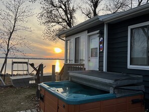 Una casa con jacuzzi y vistas a un lago al atardecer.