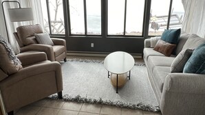 A living room with two sofas, a round coffee table, and a view of the sea through large windows. - Lakeside Getaway on Lake Madison. Hot tub with a view of the lake! (Wentworth)