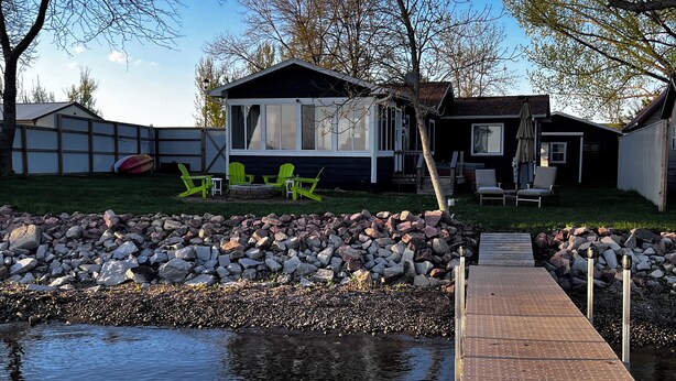 A house with a backyard featuring a pond, a wooden dock, and green Adirondack chairs. - Lakeside Getaway on Lake Madison. Hot tub with a view of the lake! (Wentworth)