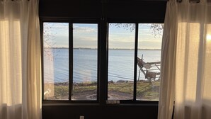A room with a large window overlooking a body of water, a chair, and a small table. - Lakeside Getaway on Lake Madison. Hot tub with a view of the lake! (Wentworth)
