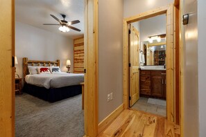 A bedroom with a bed, a ceiling fan, and a wooden headboard.