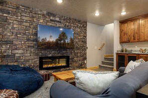 A cozy living room with a stone fireplace, a flat-screen TV, and a comfortable seating area.