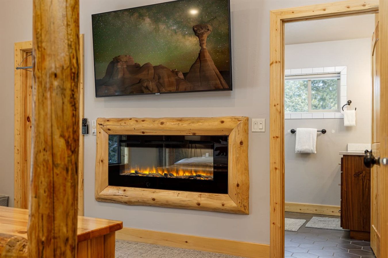 Ein Zimmer mit Kamin, einem darüber angebrachten Fernseher und einer Holztür.