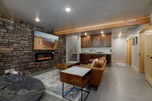 Una sala de estar con pared de piedra, chimenea, sofá, mesa de centro y alfombra.