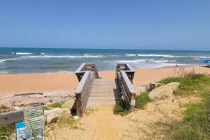 A wooden boardwalk leading to a sandy beach with ocean waves. - The Blue Dolphin Beach Cottage - Bring your bathing suit and your pup! (Ormond Beach)