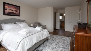 A bedroom with a bed, bedside table, lamp, and a painting on the wall. - Marvelous  Bedroom House on Comdale (Winnipeg)