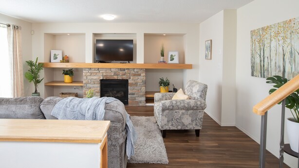 A modern living room with a fireplace, a television, and comfortable seating. - Marvelous  Bedroom House on Comdale (Winnipeg)