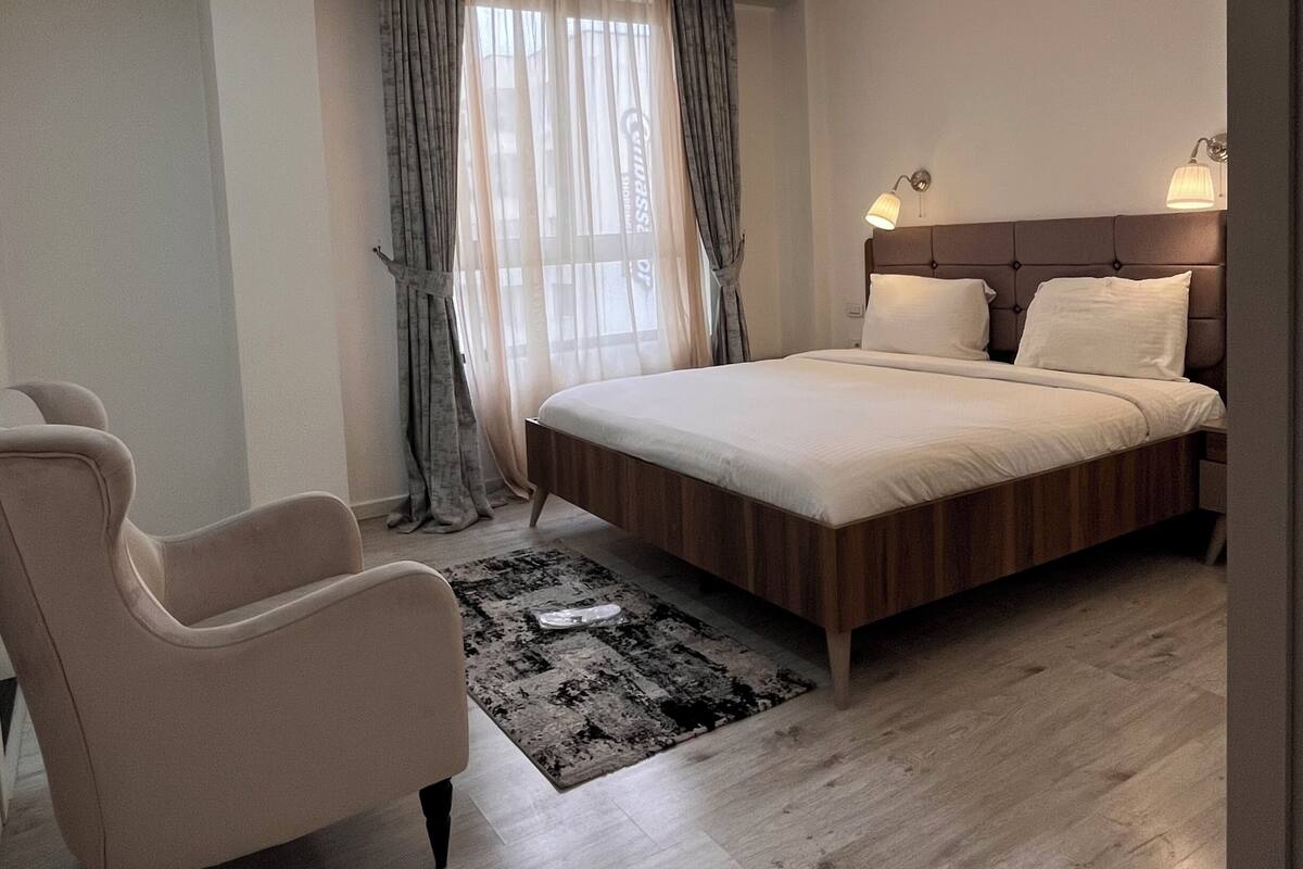 A modern bedroom with a large bed, a chair, and a rug.