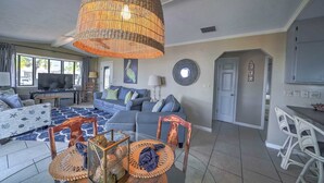 A living room with a sofa, chairs, a dining table, and a large woven light fixture.