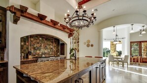 A spacious kitchen with a large island, a stone fireplace, and a dining area with a view. - Boerne Hacienda with Pool and Spa (Boerne)