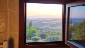 A bathroom with a window offering a view of a landscape with trees and hills. - Casa Romantica in un Borgo Antico in Sabina (Cicignano)