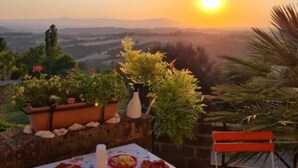 An outdoor dining table with food, a chair, and a view of the sunset over a landscape. - Casa Romantica in un Borgo Antico in Sabina (Cicignano)