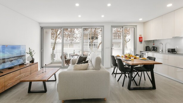 A modern living room with a sofa, dining table, and kitchen area.