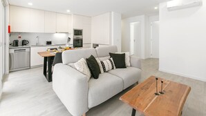 A modern apartment with a kitchen, a living area with a sofa and coffee table, and a dining table.