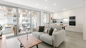 A modern living room with a sofa, a wooden coffee table, and a dining area with a table and chairs.